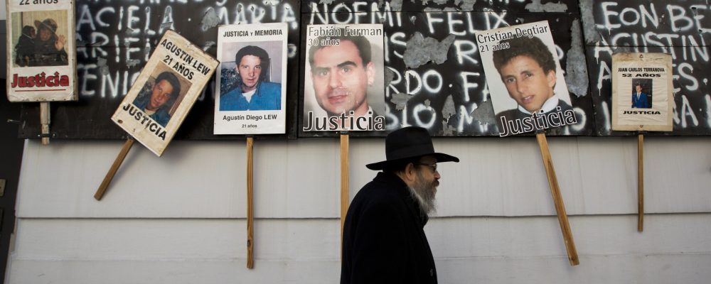 A man walks by a mural covered with names and photographs of the victims of the 1994 bombing of the AMIA Jewish community center on the 19th anniversary of the terror attack in Buenos Aires, Argentina, Thursday, July 18, 2013. The bombing of the Argentine-Israeli Mutual Association in downtown Buenos Aires killed 85 people in 1994 and remains unsolved. (AP Photo/Victor R. Caivano)