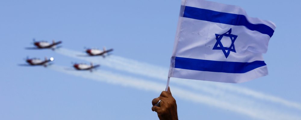 An Israeli flag waves as Israeli Air Force planes fly in formation over the Mediterranean Sea during an aerial show as part of the celebrations for Israel's Independence Day, marking the 74th anniversary of the creation of the state, in Tel Aviv, Israel May 5, 2022. REUTERS/Amir Cohen