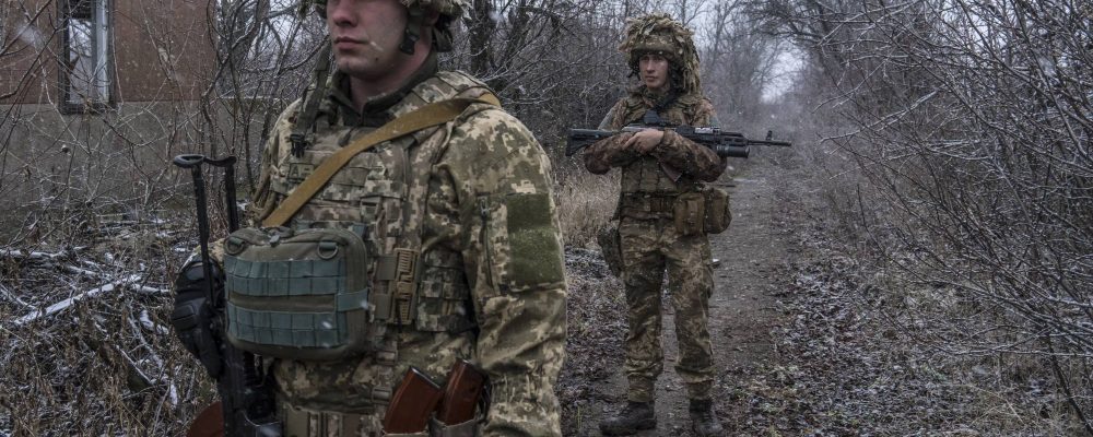 Capt. Denis Branitskii, left, and another soldier patrol a front-line position in a former neighborhood of country houses in Avdiivka, Ukraine, Dec. 1, 2021. After eight years in the trenches, Ukrainian soldiers are resigned to the possibility that the Russian military, which dwarfs their own in power and wealth, will come sooner or later. (Brendan Hoffman/The New York Times)